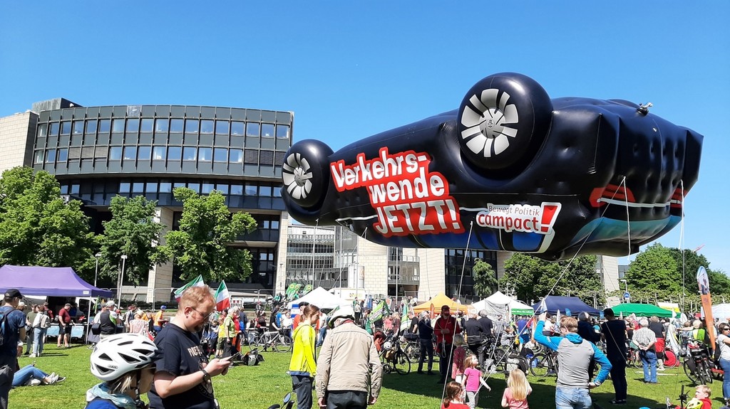 Teilnehmer*innen der Verkehrswende-Demonstration und ein großer Luftballon in Form eines PKWs, der auf sein Dach gewendet wurde