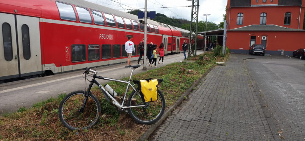 Ein RE im Bahnhof Schladern, davor Menschen und ein Fahrrad