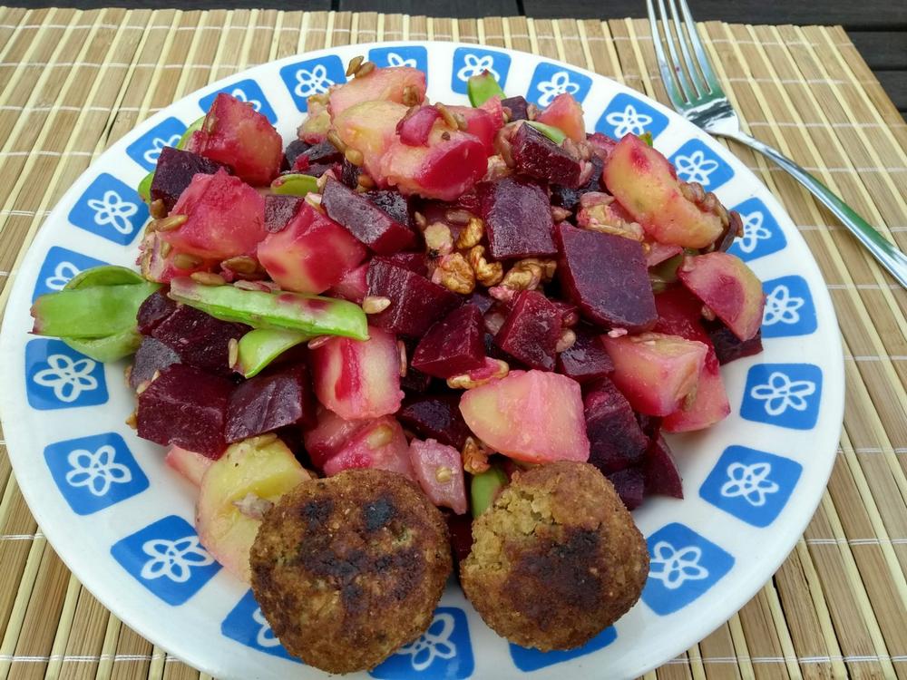 Ein Teller mit Kartoffeln, rote Bete, Schoten, Walnüssen und Falafel
