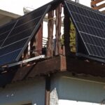 Zwei Solarpanels, die an einer hölzernen Terrassenbrüstung befestigt sind