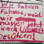 Eine Pappe mit der Aufschrift "Wir fahren Fahrrad, weiel wir müssen jetzt diereck Umwelt beschützen!"