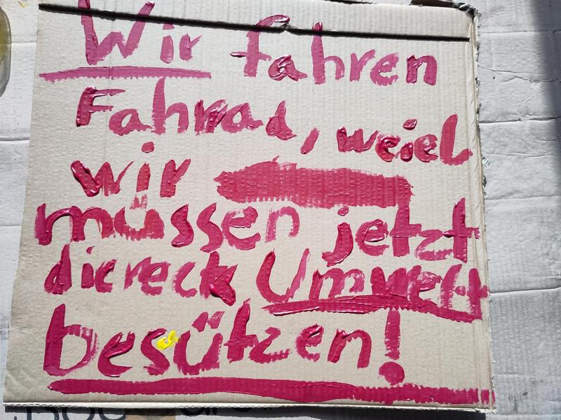 Eine Pappe mit der Aufschrift "Wir fahren Fahrrad, weiel wir müssen jetzt diereck Umwelt beschützen!"