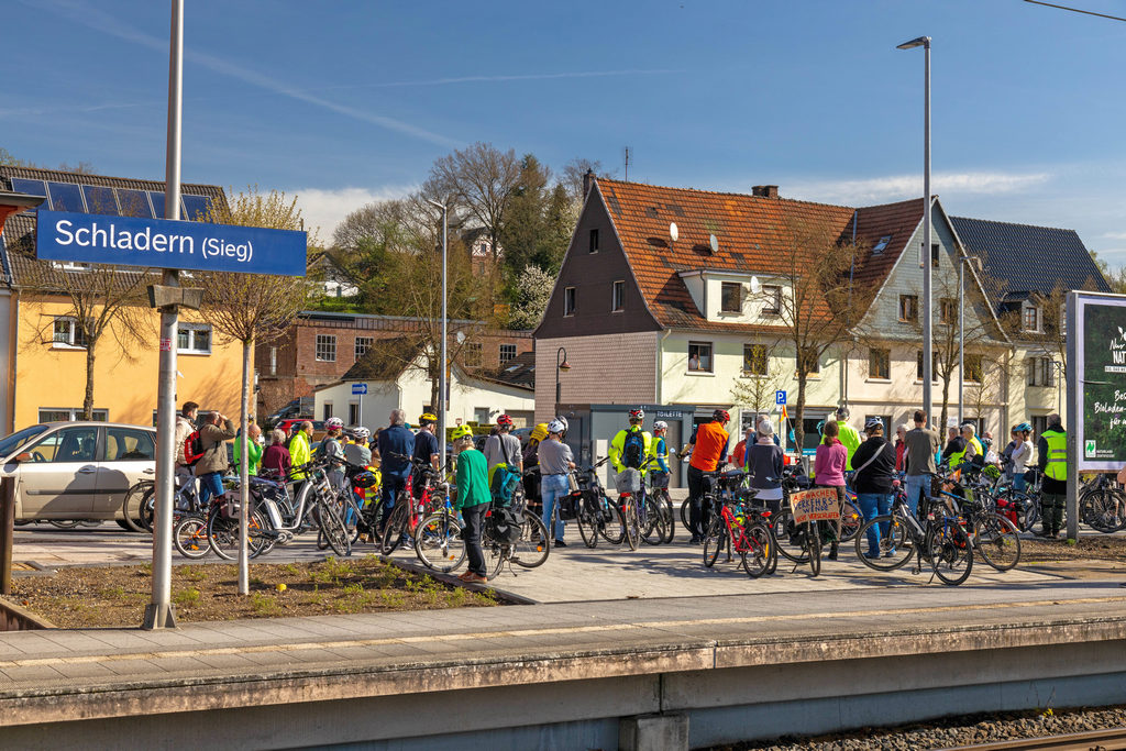 Neben dem Bahnsteig des Bahnhofs Schladern stehen die Teilnehmenden der Fahrraddemo vom 6. April 2024 und verfolgen die Redebeiträge