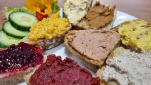 Auf einem Teller sind mehrere kleine Scheiben Brot, jeweils mit einem anderen Aufstrich.