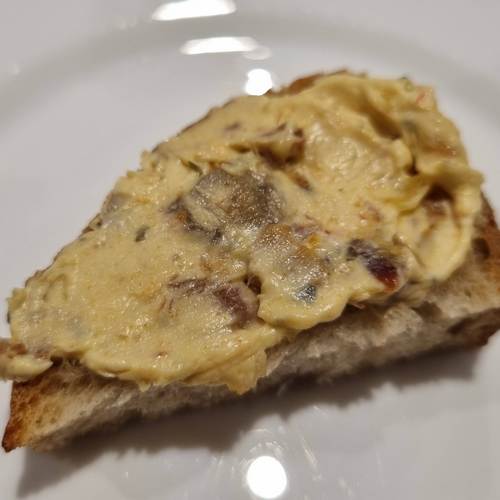 Der leicht gelbliche Aufstrich auf einer Scheibe Brot. Die Dattelstückchen sind gut zu erkennen.