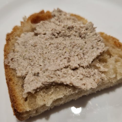 Der Nusskäse auf einer kleinen Scheibe Brot hat eine hellbeige Farbe, fast wie das Brot.