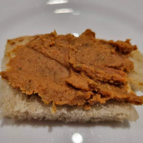 Der rostfarbene Aufstrich auf einer kleinen Scheibe Brot